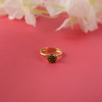 Gold ring with a gemstone on a pink background with flowers