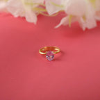 Gold ring with a pink gemstone on a red background with flowers.