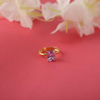 Gold ring with a pink gemstone on a red background with flowers.