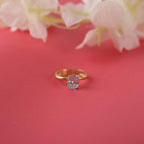 Gold ring with a pink gemstone on a red background with white flowers.