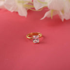 Gold ring with a radiant cut gemstone on a red background with flowers.
