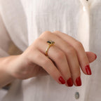 Hand wearing a gold ring with a peridot against a white background