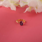 Gold ring with a purple gemstone on a pink background with flowers
