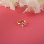 Gold ring with a pink gemstone on a red background with flowers.