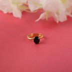 Gold ring with a black gemstone on a pink background with flowers