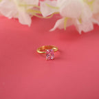 Gold ring with a pink gemstone on a pink background with flowers.