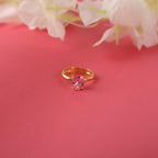 Gold ring with a pink tourmaline gemstone on a pink background with flowers