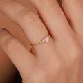 Gold ring with a pearl on a person's finger against a neutral background