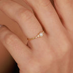 Gold ring with a pearl on a person's finger against a neutral background
