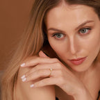 Woman wearing a gold ring with a brown background