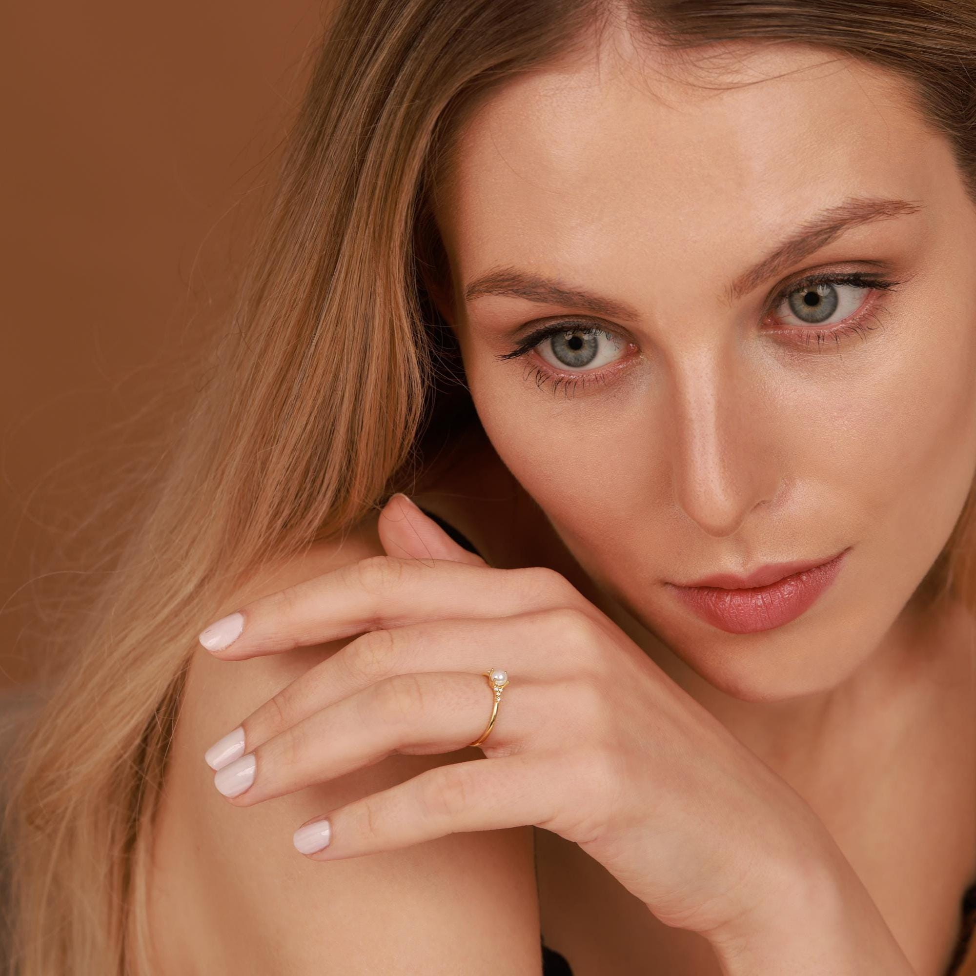 Woman wearing a gold ring with a brown background