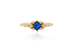 Gold ring with a blue gemstone on a white background