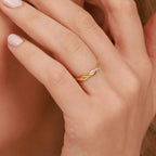 A gold ring with paved small diamonds on a person's finger against a neutral background