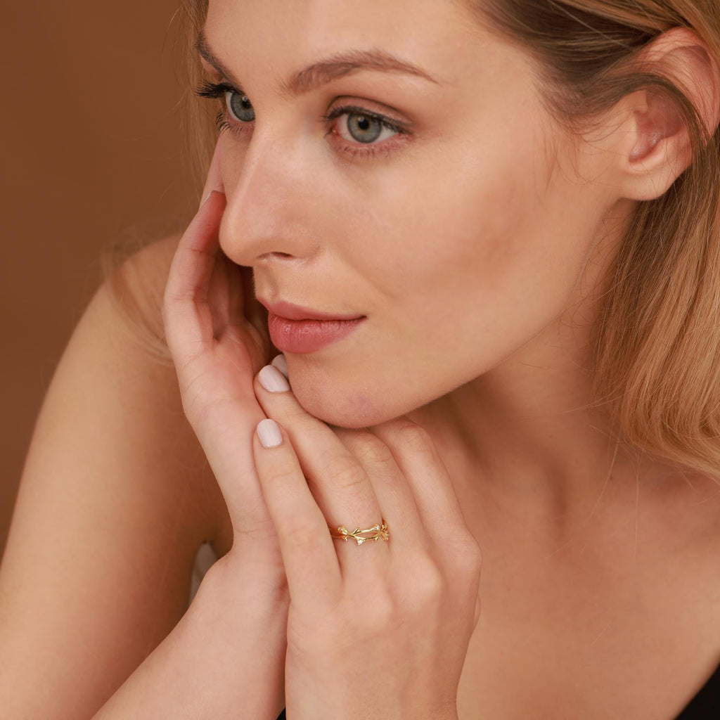 Woman wearing a gold ring on her finger with a neutral background