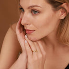 Woman wearing a gold ring on her finger with a neutral background