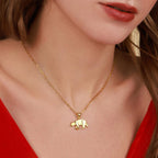 Gold necklace with a bear pendant worn by a person in a red top.