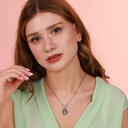 Woman wearing an oxidized christian necklace against a pink background
