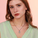 A woman wearing a Mother Mary necklace with a pink background