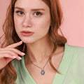 A woman wearing a miraculous necklace with a pink background
