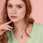 A woman wearing a miraculous necklace with a pink background