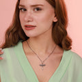 Woman wearing a necklace with an archangel sword pendant against a pink background