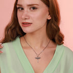 Woman wearing a necklace with an archangel sword pendant against a pink background