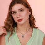 Woman wearing a green top and jesus necklace against a pink background