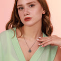 Woman wearing a st benedict coin necklace with a pink background