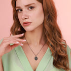 Woman wearing an archangel michael necklace against a pink background
