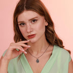 Woman wearing a green top and a religious necklace against a pink background