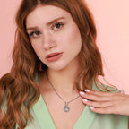 Woman wearing a necklace with an oxidized jesus pendant against a pink background