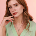 Woman wearing a sterling silver necklace with a nail cross pendant against a pink background