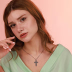 Woman wearing an oxidized silver necklace with a rose cross pendant against a pink background