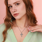Woman wearing a sterling silver necklace with an inri cross pendant against a pink background