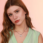 A woman wearing a green top and bear necklace with a pink background
