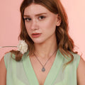 Woman wearing a green dress with an oxidized necklace against a pink background