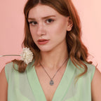 Woman wearing a green dress with an oxidized necklace against a pink background
