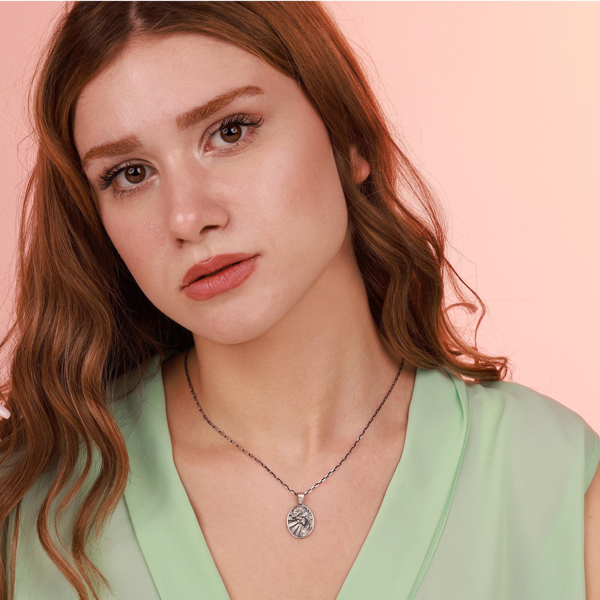 Woman wearing a jesus necklace with a pink background