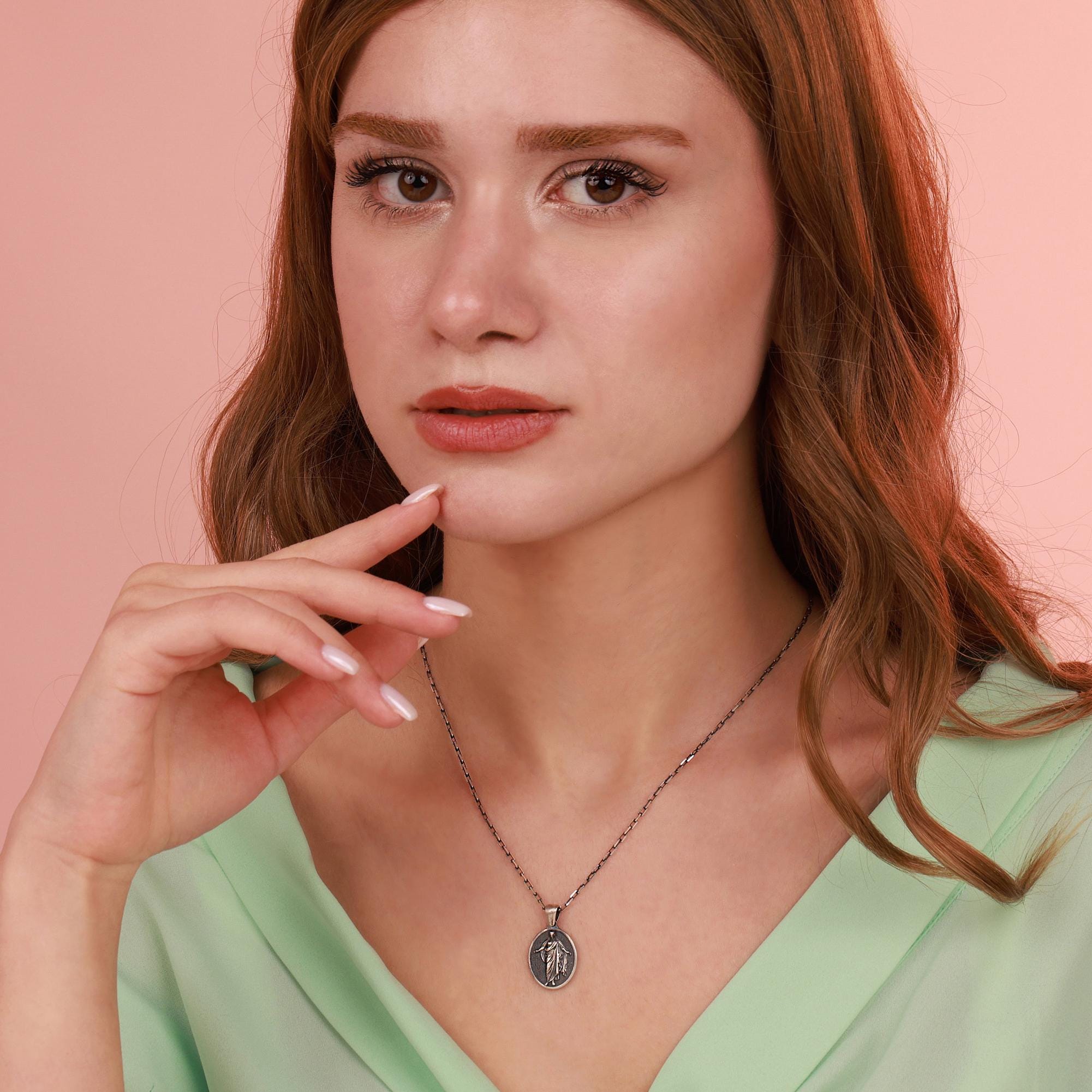 Woman wearing a resurrection jesus necklace with a pink background