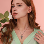 Woman wearing an oxidized silver necklace with a resurrection cross pendant against a pink background
