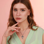 Woman wearing a necklace with a Jesus cross pendant against a pink background
