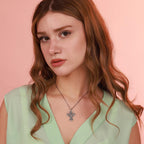 Woman wearing a green top and necklace with a cross pendant featuring the archangel against a pink background