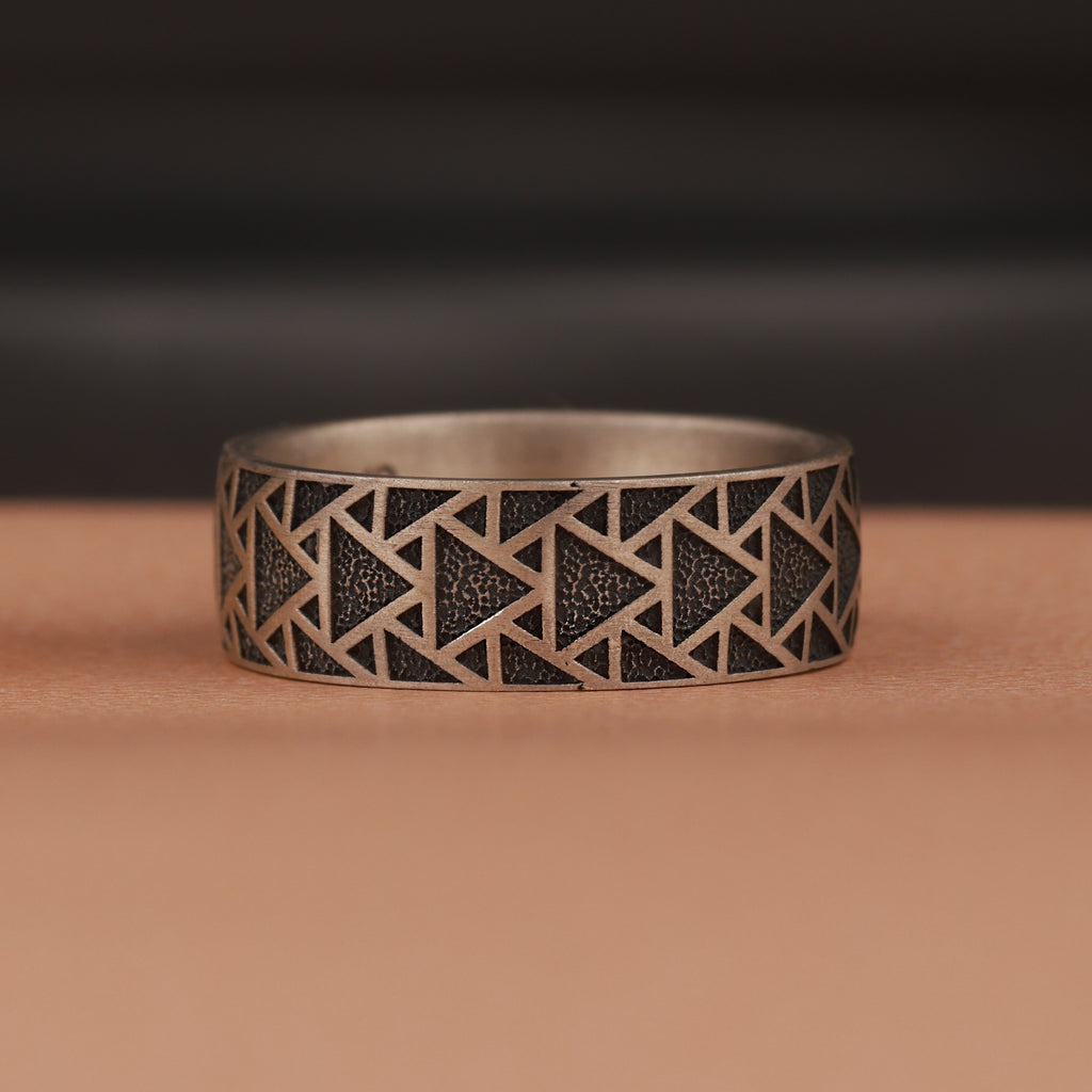 Silver ring with geometric pattern on a brown surface