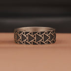 Silver ring with geometric pattern on a brown surface