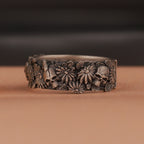 Silver band with skull floral patterns on a brown surface