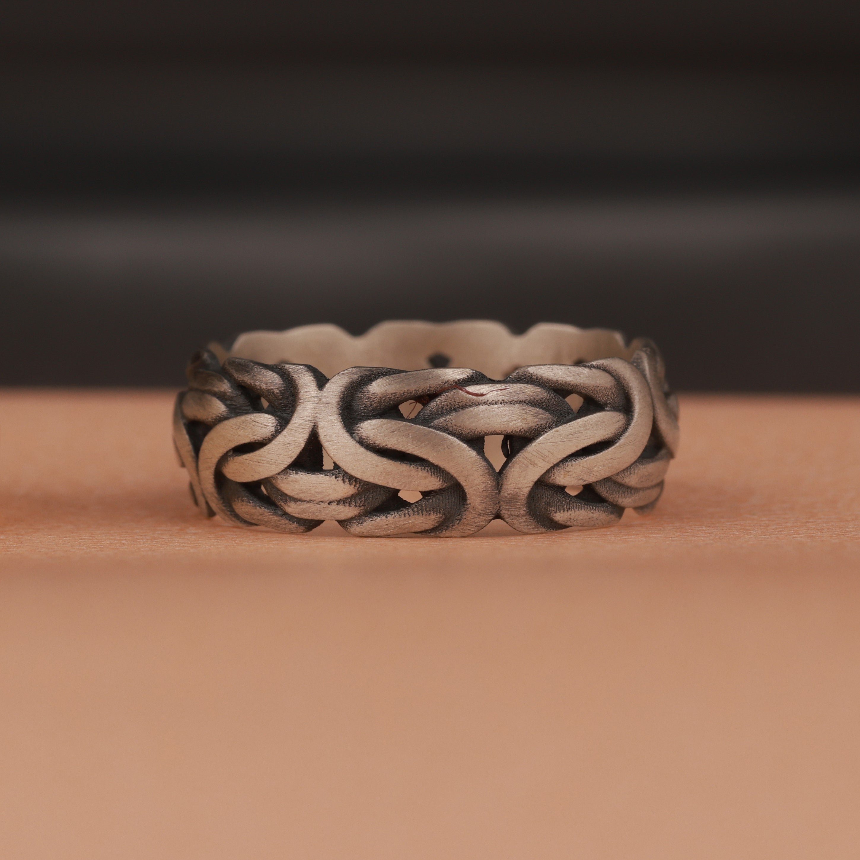 An oxidized silver ring on brown and dark background