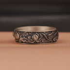 Silver ring with intricate floral patterns on a brown background
