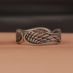 Bronze ring with wing design on a brown surface