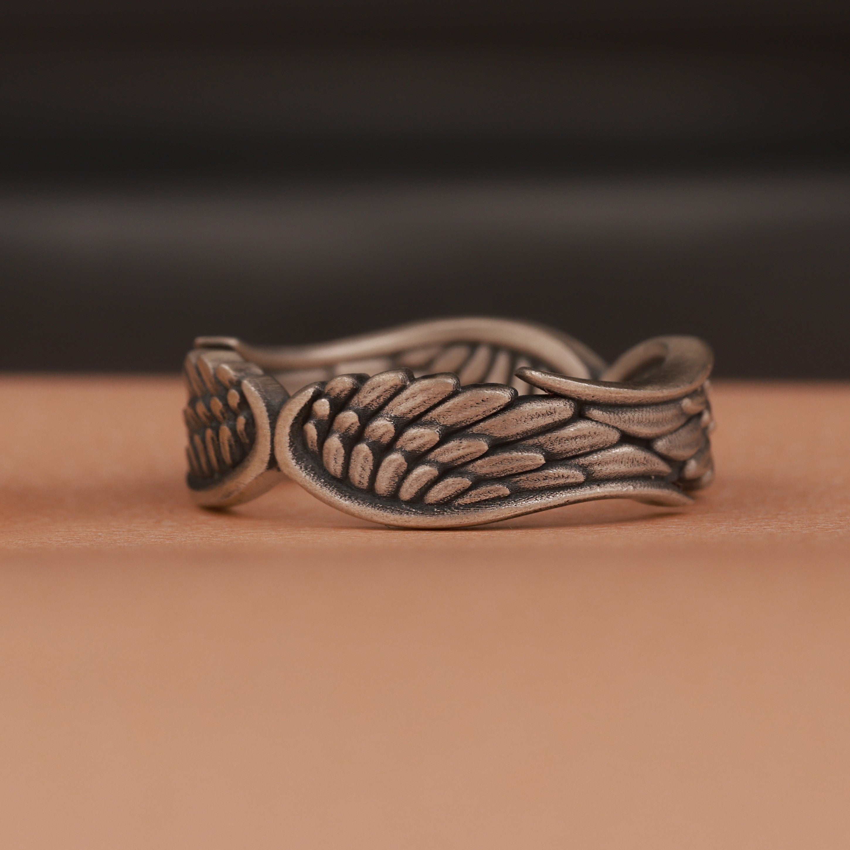 Bronze ring with wing design on a brown surface
