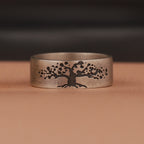 Silver ring with an engraved tree design on a brown background